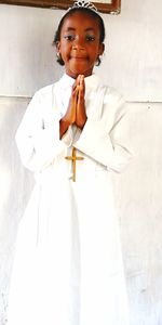 Portrait of a smiling young woman standing against white wall