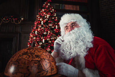 Man wearing santa claus costume by globe at home