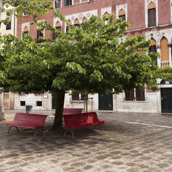 Empty bench in park against buildings in city