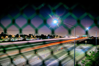 Light trails seen through chainlink fence at night
