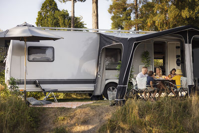 Family relaxing in front of camper trailer