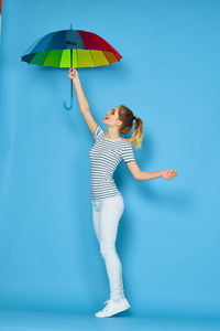 Woman holding umbrella standing against blue sky