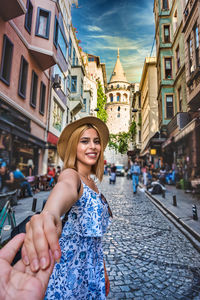 Portrait of smiling woman on street against buildings in city