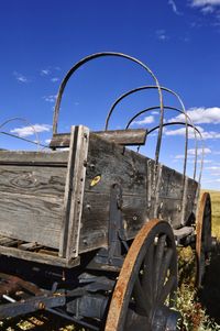 Close-up of cart on field against blue sky