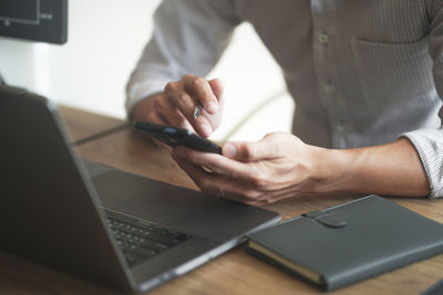 Midsection of man using laptop on table