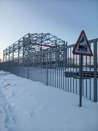 Road sign on snow covered land against sky
