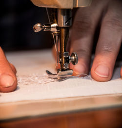 Cropped hands of person working on sewing machine