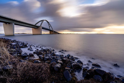 Bridge over sea against sky during sunset