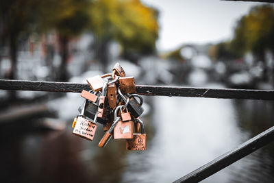 Low angle view of padlocks on railing by river