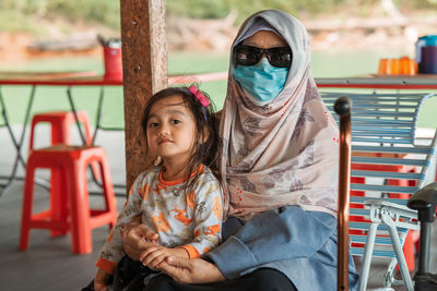 Portrait of senior woman with granddaughter sitting outdoors