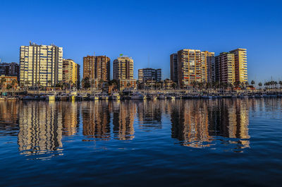 Reflection of buildings in river against blue sky