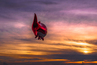 Low angle view of fish shape helium balloon against cloudy sky during sunset