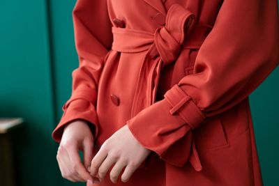 Midsection of woman standing against red wall