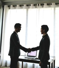 Businessmen shaking hands while standing in office