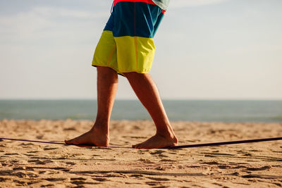 Low section of man walking at beach