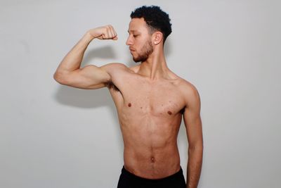 Midsection of shirtless man standing against white background