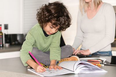 Smiling male child focused drawing on a book