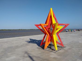 Traditional windmill on beach against clear blue sky