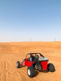 Tractor on desert against clear sky