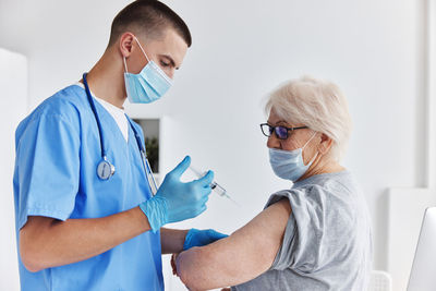 Doctor wearing mask vaccinating patient