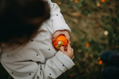 Midsection of girl holding orange outdoors