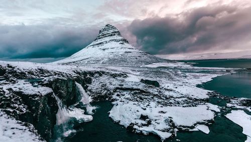 Scenic view of snow covered mountain against cloudy sky