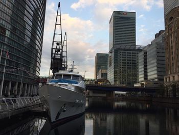 Modern buildings by canal against sky in city