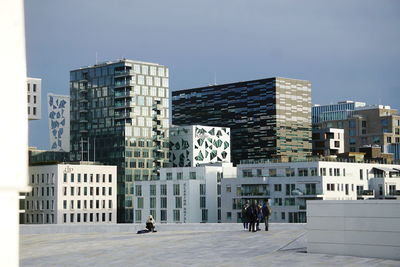 People on modern building against sky in city