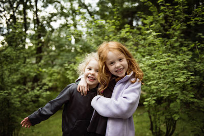 Portrait of happy sisters standing in backyard