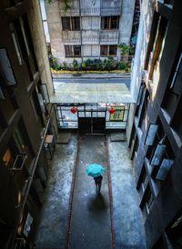 High angle view of woman walking with umbrella on footpath of building