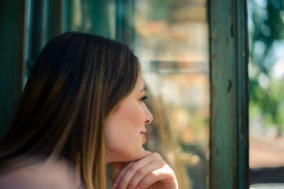 Smiling young woman looking through window