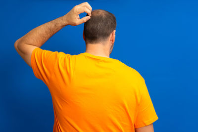 Rear view of man standing against blue background