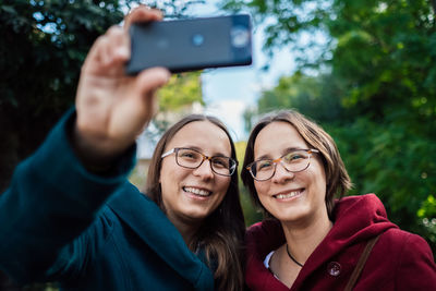 Smiling twins taking selfie with smart phone