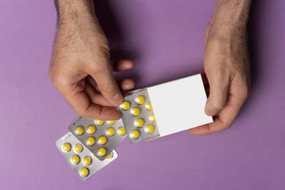 Cropped hands of woman holding pills against blue background