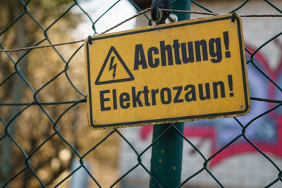 Close-up of warning sign on chainlink fence