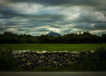 Stack of stones on field against sky