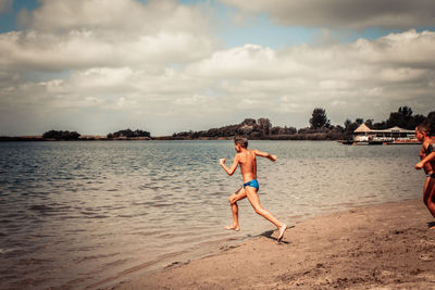 Happy kids running in the water and having fun on the beach in summer.