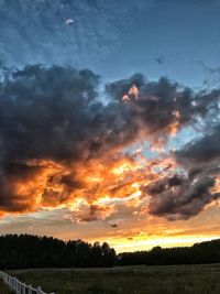 Scenic view of dramatic sky over silhouette field