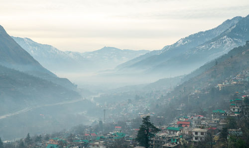 Aerial view of townscape and mountains against sky