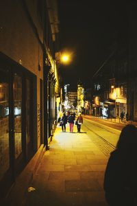 People in illuminated city against sky at night