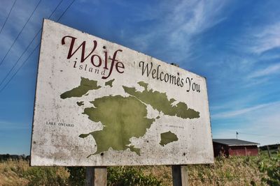 Low angle view of sign board against blue sky