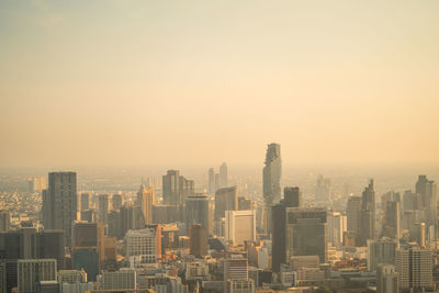 Modern buildings in city against sky at sunset