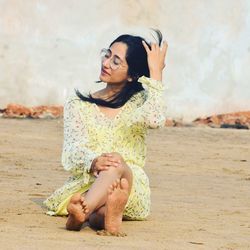 Young woman sitting on sand at beach