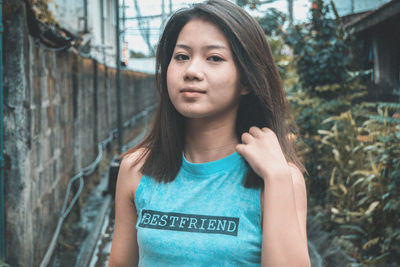 Portrait of beautiful young woman standing against trees