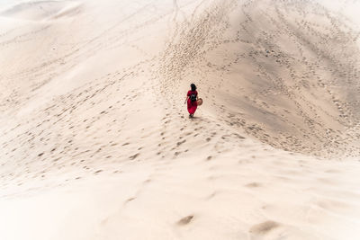 Rear view of woman walking on sand at beach