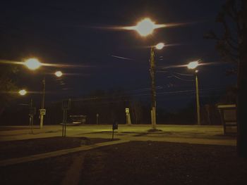 Illuminated street lights against sky at night