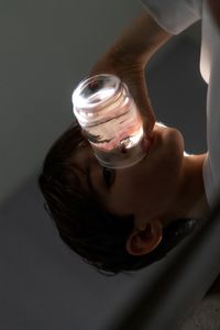 Close-up of boy drinking water by drinking glass at home