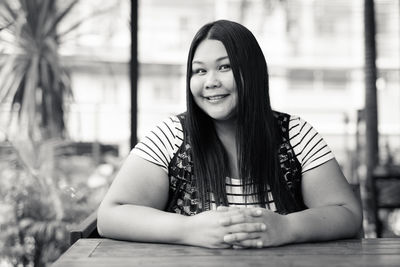 Portrait of smiling young woman sitting on table