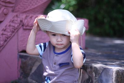 Cute boy wearing hat sitting outdoors