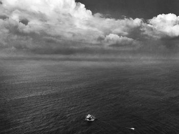 Boat in sea under cloudy sky